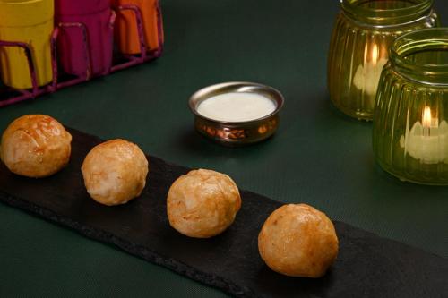 a group of three balls of food on a black plate at The Mirador in Mumbai