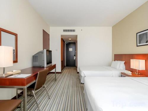 a hotel room with two beds and a desk at RH Hotel Sibu in Sibu
