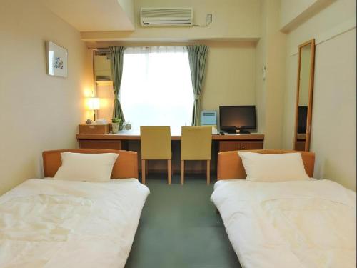 a room with two beds and a table and a desk at Refre Forum in Tokyo