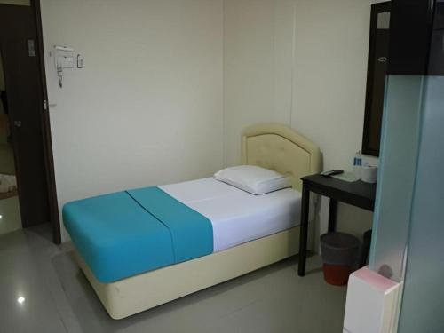a small bedroom with a bed and a table at Rafayeh Hotel in Seremban