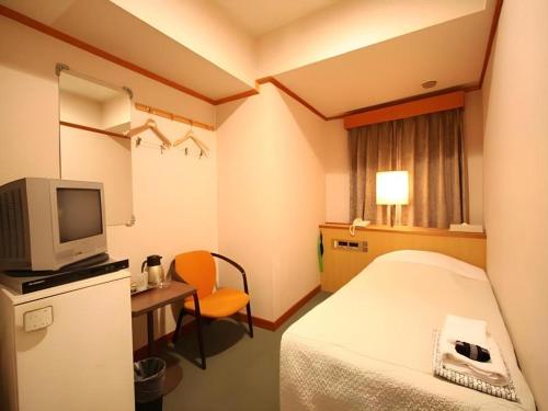 a hotel room with a bed and a desk and a tv at Okinawa Sunplaza Hotel in Naha