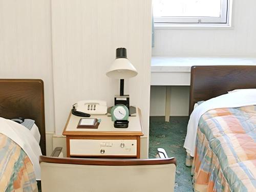 a hotel room with two beds and a table with a lamp at Hotel Abest Aomori in Aomori