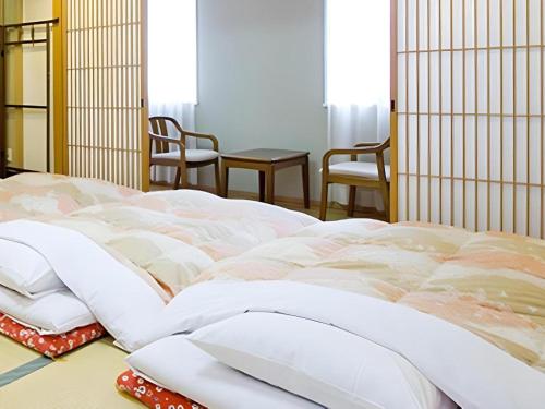 a large white bed in a room with chairs at Hotel Abest Aomori in Aomori