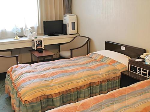 a hotel room with two beds and a desk with a computer at Hotel Abest Aomori in Aomori