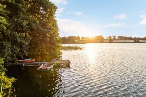 a boat is docked at a dock on a lake at GUT KLETKAMP "Finkenhaus" - Idyllisch freistehendes Landhaus mit 3 Schlafzimmern und fantastischem Ausblick I 8 Personen I Offener Kamin I Garten I Wintergarten I Große Terrasse I Ruhig am Waldrand I Parkplätze I WLAN in Kletkamp