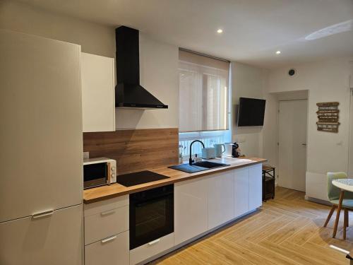 eine Küche mit weißen Schränken und einer Mikrowelle in der Unterkunft Le 325 Appartement de qualité avec terrasse in Béthune
