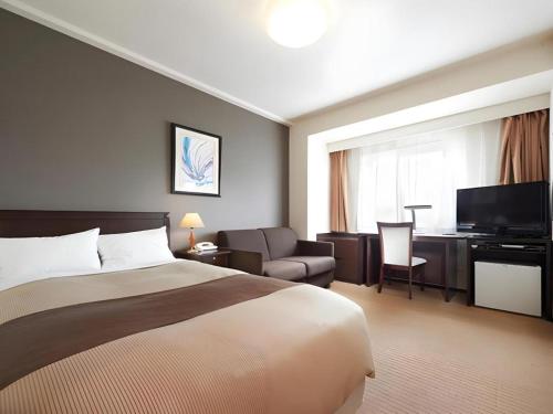 a hotel room with a bed and a couch and a television at Hotel Sealuck Pal Utsunomiya in Hanawadamachi