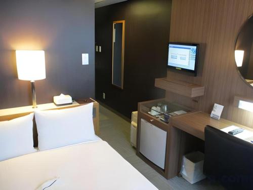 a hotel room with a bed and a television at Niigata Keihin Hotel in Niigata