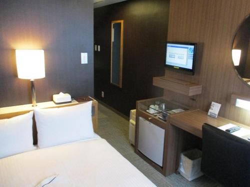 a hotel room with a bed and a television at Niigata Keihin Hotel in Niigata