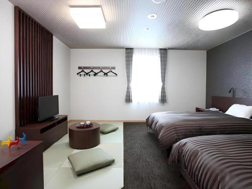a bedroom with two beds and a television in it at Hotel Ligare Kasugano in Nara