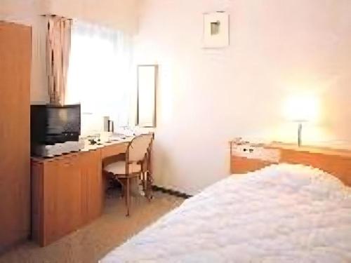 a bedroom with a desk with a computer and a bed at Mimatsu Hotel in Mito