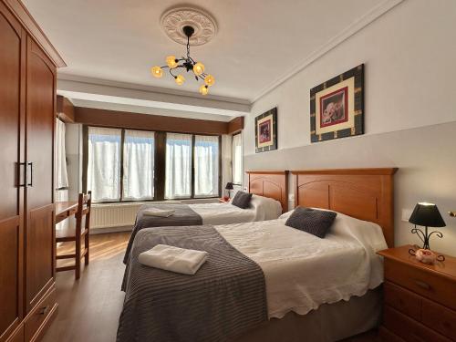 a bedroom with two beds and a chandelier at Casa Leuza in Espronceda