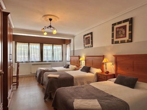 a hotel room with three beds and a window at Casa Leuza in Espronceda