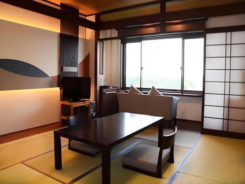 a room with a table and chairs and a television at Ikadasou Sanjou in Shima