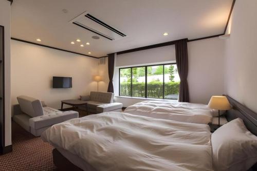 a bedroom with a large white bed and a window at Hotel Silk Onsen Yamabiko in Izushi