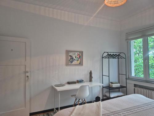 a white bedroom with a desk and a bed at Résidence Souverain 94 in Brussels