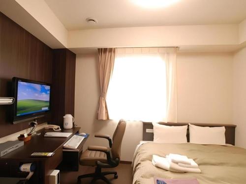 a hotel room with a bed and a desk with a computer at Chino Station Hotel in Chino