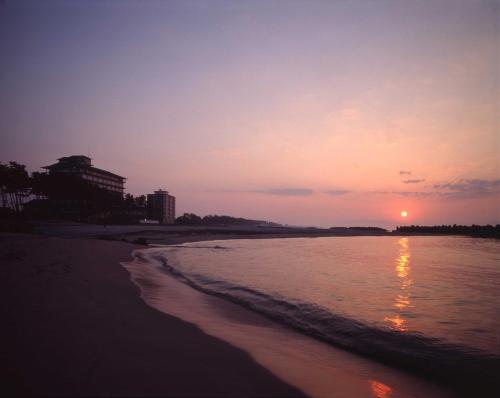 a sunset on a beach with the ocean at Kasuitei in Yonago