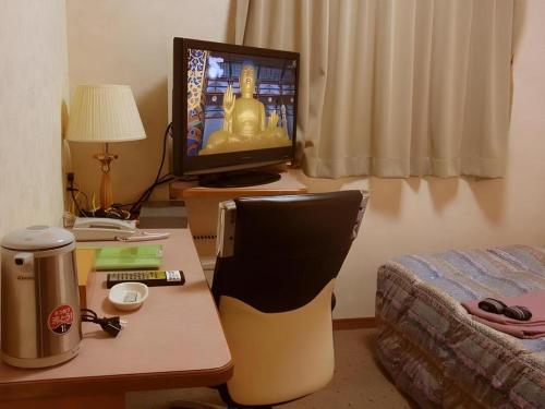 a room with a desk with a television and a bed at Chino Station Hotel in Chino