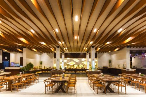 a restaurant with wooden ceilings and tables and chairs at The Cliff Resort & Residences in Mui Ne