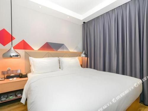 a bedroom with a large white bed and a window at Borrman Hotel Zhuhai Gongbei Port Fuhuali Light Rail in Zhuhai