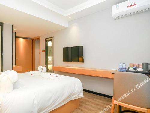 a hotel room with a white bed and a desk at Borrman Hotel Zhuhai Gongbei Port Fuhuali Light Rail in Zhuhai