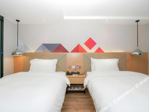 two beds sitting next to each other in a room at Borrman Hotel Zhuhai Gongbei Port Fuhuali Light Rail in Zhuhai
