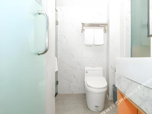a white bathroom with a toilet and a sink at Borrman Hotel Zhuhai Gongbei Port Fuhuali Light Rail in Zhuhai