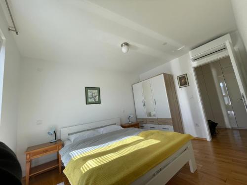 a bedroom with a bed with a yellow blanket on it at Apartman Damir in Malinska