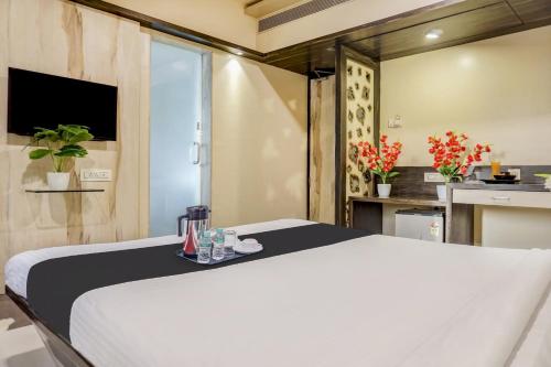 a bedroom with a white bed and a kitchen at Super Townhouse OAK Regal Inn Near Sant Tukaram Nagar Metro Station in Pune
