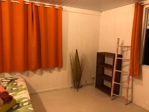 a bedroom with an orange curtain and a shelf at Fare Mirimiri in Uturoa