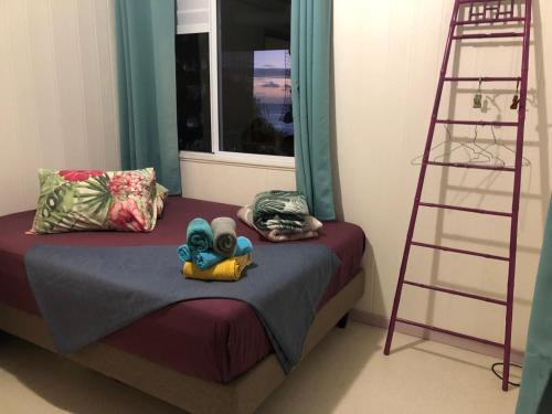 a bedroom with a bed with a ladder next to a window at Fare Mirimiri in Uturoa