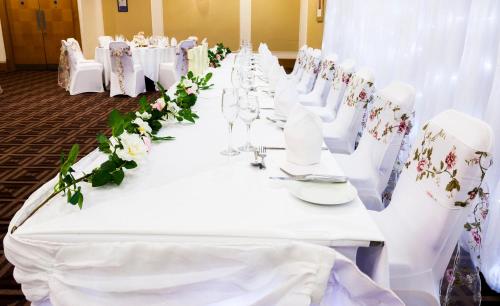 a row of tables with white chairs and flowers at Holiday Inn Newcastle Gosforth Park by IHG in Newcastle upon Tyne