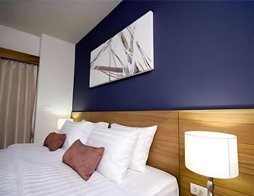 a bedroom with a white bed with a blue wall at Pannapat Place in Bangkok