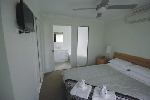 a bedroom with a bed and a flat screen tv at Broke Village Hideaway in Broke