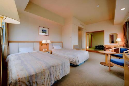 a hotel room with two beds and a table at Grand Hotel New Oji in Tomakomai