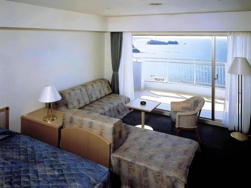 a hotel room with a bed and a couch and a window at Hotel Harvest Nankitanabe in Tanabe