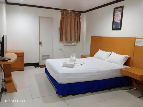 a bedroom with a bed and a desk and a television at Jeamco Royal Hotel - Pasig in Manila