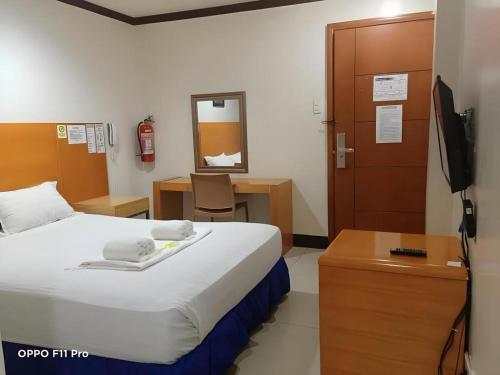 a bedroom with a bed and a desk and a television at Jeamco Royal Hotel - Pasig in Manila