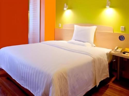 a bedroom with a large white bed with orange walls at 7 Days Inn Baoding Railway Station in Baoding