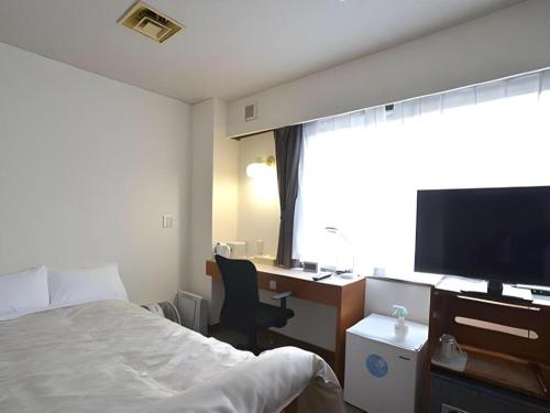 a hotel room with a bed and a desk with a television at Hamakan Hotel in Unzen