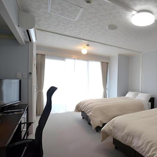 a hotel room with two beds and a flat screen tv at Hamakan Hotel in Unzen