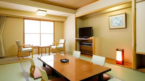 a room with a table and chairs and a television at Yuzawa New Otani in Yuzawa