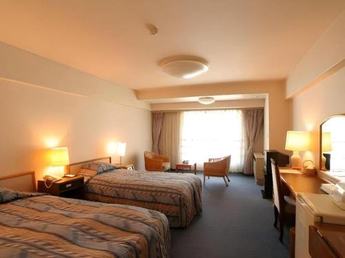 a hotel room with two beds and a desk at Yuzawa New Otani in Yuzawa