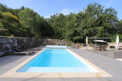 une piscine avec des chaises et un mur en pierre dans l'établissement A l'ombre du Ventoux, à Saint-Romain-en-Viennois