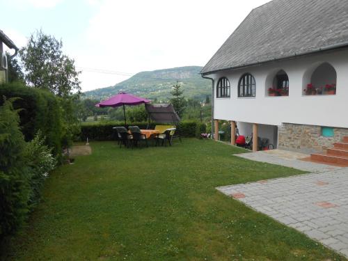 a yard with a table and chairs and a house at Panoráma Holiday Home in Badacsonyörs