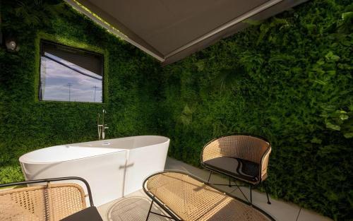 a bathroom with a green wall with a tub and chairs at HOTEL D EDITION in Daejeon
