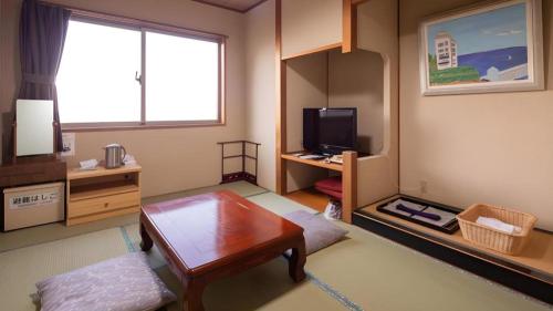 a living room with a table and a television at Hotel AreaOne Banjinmisaki in Kashiwazaki