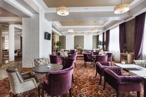 a restaurant with purple chairs and tables and a bar at Mask Business Hotel in Pyatigorsk