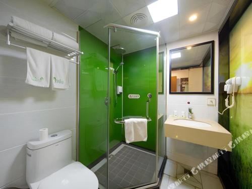 a green bathroom with a toilet and a sink at Vatica Shanghai Pudong Dishui Lake Branch in Shanghai